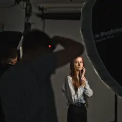 Sesja zdjęciowa w studiu. Fotograf z aparatem, modelka i oświetlenie. Inspiracja dla blogi o fotografii.