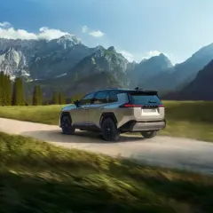 Srebrny Toyota RAV4 pokonuje szutrową drogę w górskim krajobrazie. Idealny do przygód off road.