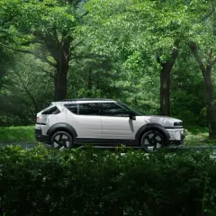 Biały Tucson Hybrid na tle zielonego lasu. Niskie spalanie to jego atut podczas podróży po malowniczych trasach.