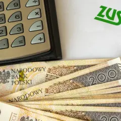 Kalkulator, banknoty 200 zł i logo ZUS. Obliczenia dotyczące tego, ile wynosi dodatek do emerytury za warunki szkodliwe.