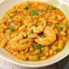Plato de verdinas con langostinos, guisadas en una salsa sabrosa y adornadas con perejil fresco.