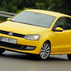 Żółty Volkswagen Polo 6R na mokrej drodze, z tablicą rejestracyjną PO 401LL.
