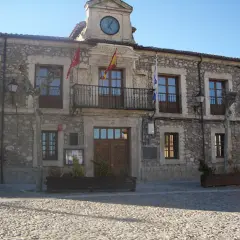 Ayuntamiento de Lozoyuela, con su fachada de piedra, balcón y reloj. Un lugar con mucho que ver.