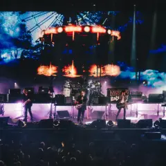 The Cure Polska na żywo. Zespół gra na scenie, w tle wielki ekran z karuzelą.