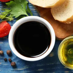 Sos do czego? Ocet balsamiczny, oliwa, pomidorki i pieprz na niebieskim tle. Idealne składniki na pyszną sałatkę.
