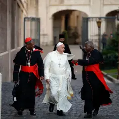 Papst Franziskus geht mit zwei Kardinälen. Was macht der Papst den ganzen Tag? Er spricht, betet und kümmert sich um die Menschen.