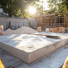 Chantier de construction : une dalle de béton fraîchement coulée, des sacs de ciment et du sable. Faut-il déclarer une terrasse en béton ?