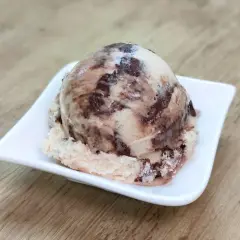Ein Löffel cremiges Kinderriegel Eis mit Schokoladenstückchen auf einer weißen Schale.