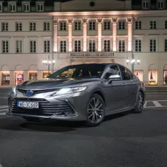 Elegancka, szara Toyota Camry 2024 zaparkowana nocą przed zabytkową kamienicą.