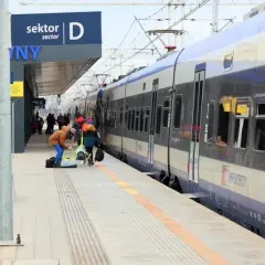 Praca ustawiacz kolejowy na dworcu. Ludzie z bagażami czekają na pociąg PKP Intercity.