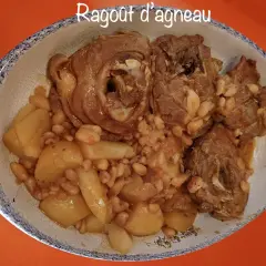 Un plat de ragout d'agneau avec des pommes de terre et des haricots blancs, servi dans un plat ovale à bordure bleue.