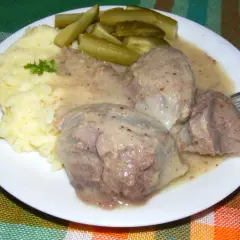 Na talerzu puree ziemniaczane, sos i żołądki z indyka, obok ogórki kiszone.