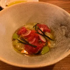 Un plato de mariscos con tomate picado, rábano y algas, servido en una **taberna oeste**.