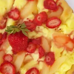 Słodka pizza z kremem budyniowym, truskawkami i kawałkami gruszek. Idealna na deser.