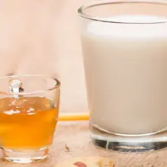 Szklanka miodu i mleka, obok pomarańczowy miodownik. Zastanawiasz się, ile waży szklanka miodu?