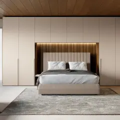 Una moderna zona notte all'ingresso, con letto centrale, armadi a muro e un pouf.