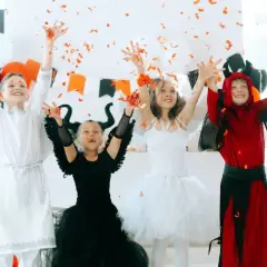 Dzieci w strojach aniołów i diabła rzucają konfetti.