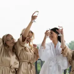 Radosne panny młode w szlafrokach wznoszą toasty. Zastanawiasz się nad wedding planner cena?