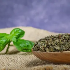 Świeża bazylia obok łyżki suszonej bazylii. Dowiedz się, jak suszyć bazylię, by zachować jej aromat.