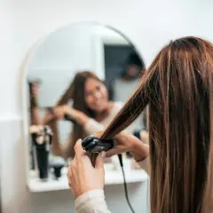 Mujer se alisa el pelo mojado frente al espejo.
