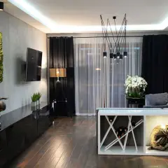 Nowoczesny salon w stylu klasycznym z zielonymi panelami ściennymi, rzeźbami i designerskim oświetleniem.