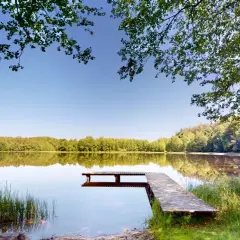 Idealne miejsce na weekend na Kaszubach: spokojne jezioro, drewniane molo i łódka czekają na wypoczynek wśród zieleni.