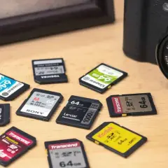 Viele SD-Karten mit 64 GB Speicherplatz liegen neben einer Kamera. Was ist das? Kleine Speicherwunder für Fotos und Videos!