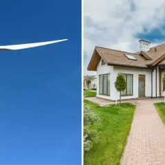 Biała turbina wiatrowa na tle błękitnego nieba obok nowoczesnego domu z zielonym trawnikiem.