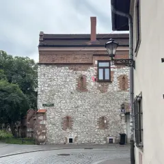 Kamienna ściana z ceglanymi elementami, przypominająca najstarszy dom w Polsce. Ulica Św. Krzyża.