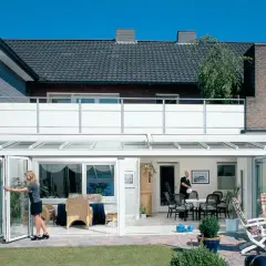 Nowoczesny balkon dostawny do domu jednorodzinnego, z przeszklonym ogrodem zimowym i składanymi drzwiami.