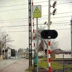 Kamery na przejazdach kolejowych monitorują bezpieczeństwo. Na zdjęciu widać sygnalizację świetlną, rogatki i kamery nadzorujące.