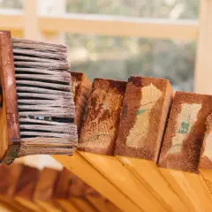 Rękawica w żółtej rękawicy nakłada lakierobejcę na drewno. Czas schnięcia zależy od warunków.