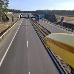 Żółta kamera rejestruje prędkość na drodze. To system odcinkowy pomiar prędkości, który dba o bezpieczeństwo kierowców.