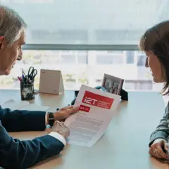 Hombre y mujer revisan un documento para firmar un NDA. El hombre señala un punto en el papel.