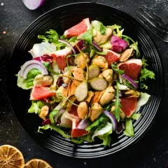 Ensalada fresca con mejillones, pomelo y cebolla morada, aderezada con mostaza de Dijon.