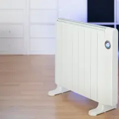 Calentador blanco emitiendo un suave calor azul. Un sofá beige y armarios blancos completan la escena.