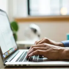 Dłonie piszą na laptopie, ekran wyświetla dane, być może związane z wmi provider host.