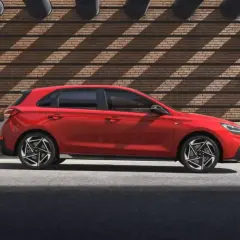Czerwony Hyundai i30 hatchback stoi na tle ceglanej ściany z ciekawymi cieniami.