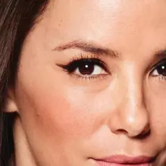 Primer plano de una mujer con pelo fosco y oscuro, ojos marrones con delineado cat eye y piel con rubor.