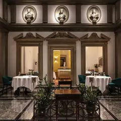Lussuoso ristorante con tavoli apparecchiati, busti antichi e colonne. Un'atmosfera da vero atto di vito mollica.