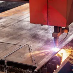 Precyzyjne cięcie plazmą metalowej płyty, iskry sypią się podczas pracy maszyny.