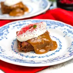 En bit saftig sockerkaka med pepparkakskrydda, toppad med vispad grädde och strössel. Serveras på en vacker blåvit tallrik.