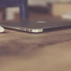 Elegancki, zamknięty laptop biznesowy i biała myszka na drewnianym biurku. Idealny zestaw do pracy.