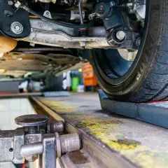 Podczas regulacji zbieżności kół w warsztacie samochodowym, mechanik precyzyjnie ustawia zawieszenie.