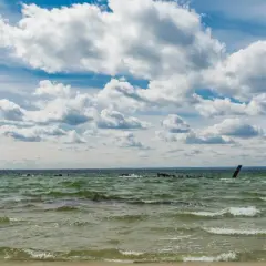 Falujące morze bałtyckie, które jest częścią oceanu atlantyckiego, pod błękitnym niebem z kłębiastymi chmurami.
