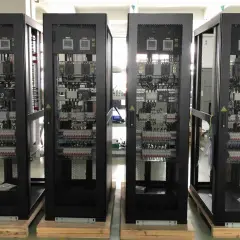 Cuatro racks negros con equipos electrónicos visibles a través de rejillas, parte de un cuarto de comunicaciones.