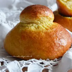 Brioches siciliane ricetta originale con strutto, dorate e soffici, su un pizzo bianco.