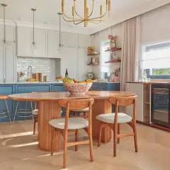Jadalnia w stylu mid century modern z owalnym drewnianym stołem, krzesłami i wyspą kuchenną.