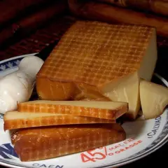 Wędzony ser na talerzu z napisem "Camembert". Obok kawałki sera i biały ser. Idealny do solanki do sera do wędzenia.