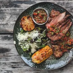 En tallrik med saftigt grillat secreto iberico, serverat med grillad majskolv, citron och en fräsch salsa. Ett perfekt secreto iberico recept för en festmåltid.